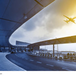 Flughafenterminal mit startendem Flugzeug bei Sonnenuntergang