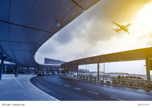Flughafenterminal mit startendem Flugzeug bei Sonnenuntergang